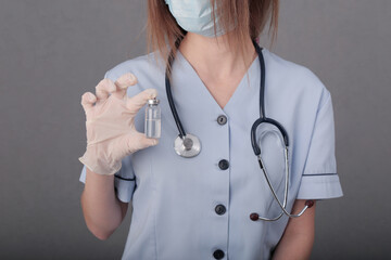woman doctor in medical mask and gloves. close-up. holds an ampoule with a vaccine in his hands. covid.