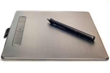 Black graphic tablet with white dots on a white background in vertical position with the pencil...