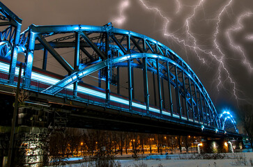 Naklejka premium Die Deutschherrnbrücke, eine Stahlbogenbrücke in Frankfurt am Main bei Nacht und Gewitter