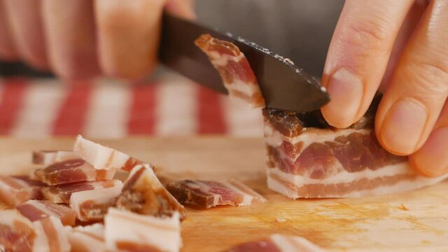 A Closeup of female hands cutting a becon on a wooden surface