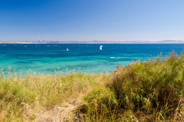 Fototapeta na wymiar Beautiful seascape with blue sky and Atlantic ocean. A lot of kiteboarders trainig. Morocco and mount Jebel Musa on the background. Punta Paloma beach, Tarifa, Provence of Cadiz, Spain.