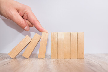 Hand stopping wooden domino business crisis effect