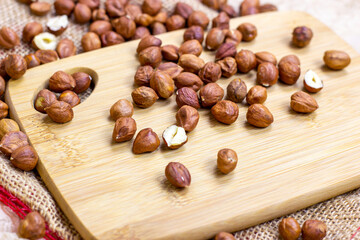 Peeled brown hazelnuts on wooden board and textile background.