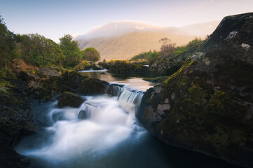 Naklejka na ściany i meble Beautiful sunrise landscape scenery with small waterfall on river Erriff with mountains in the background at Aesleagh, county Mayo, Ireland 