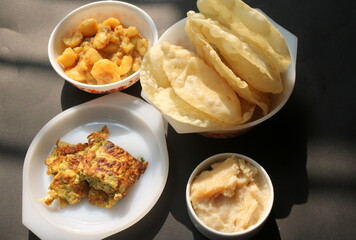 Alur dom, egg omelette and halwa with. luchi on black background. Bengali traditional breakfast.