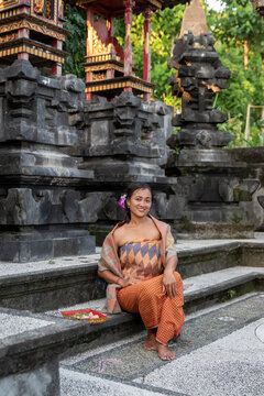 Portrait young woman with balinese face, wearing dress traditional Bali sarong in home temple. 