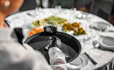 Waiter serving red wine glass in
restaurant