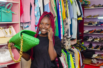 Black beautiful Nigerian girl with rasta red hair holding a phone and a handbag at the BOUTIQUE