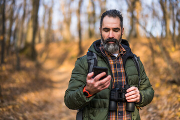 Image of hiker using phone while spending time in nature.