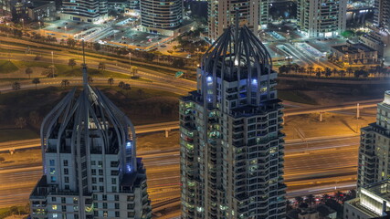 Dubai Marina and JLT district with traffic on highway between skyscrapers aerial night timelapse.