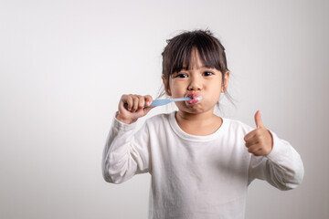 Little cute baby girl cleaning her teeth with toothbrush on white background