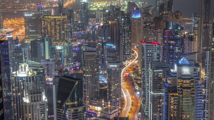 Skyline view of Dubai Marina showing canal surrounded by skyscrapers along shoreline all night timelapse. DUBAI, UAE