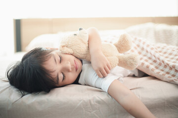 Obraz na płótnie Canvas child little girl sleeps in the bed with a toy teddy bear