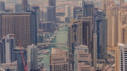 Skyline view of Dubai Marina showing an artificial canal surrounded by skyscrapers along shoreline all day timelapse. DUBAI, UAE