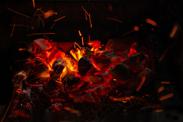 Fototapeta na wymiar Sparks of fire on a black background. flame of fire with sparks. Burning red hot sparks fly from hot coals in the fire. Beautiful abstract background on the theme of fire, light and life.