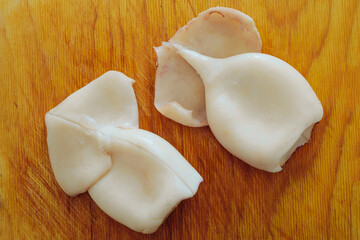 Seafood. Boiled and peeled squid tubes on a wooden cutting board.