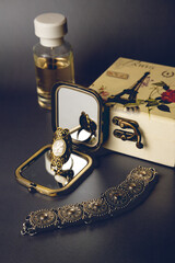 The ring is reflected in the mirror, there are perfumes nearby, a jewelry box and a metal bracelet