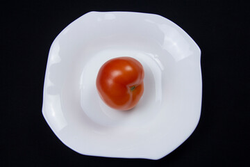 Tomato on a white plate on a black table