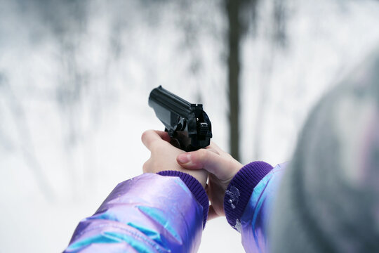 Rear view. Children's hands are thrown with a pistol with a cocked trigger. Winter.