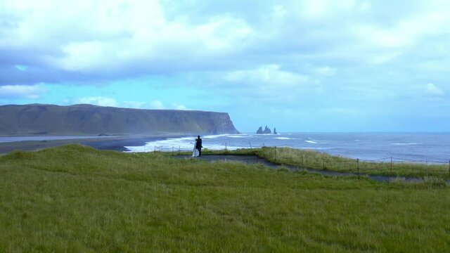 aerial slow motion panoramic view of two newlyweds stand on the edge of a cliff
