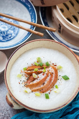 Beige bowl with chicken congee or a type of asian rice porridge, vertical shot, middle close-up