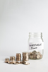 Concept of investing money for retirement and growing value over time, piles of silver coins compounding and growing next to a jar with coins in