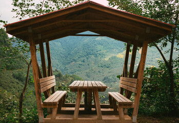 Obraz premium Wooden gazebo, picnic, camping table and benches for Relaxation with view of Forest