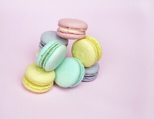 A lot of cakes, pasta of different colors colorful blue, yellow, green, round pasta on a purple background lie one on one. French sweet cookies. For the holiday, birthday, advertising confectioners.