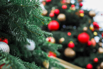 Beautiful green branches against the background of a decorated Christmas tree with red and gold balls. Stylish fair and decorations