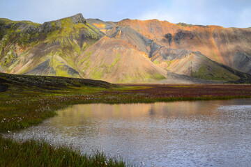 A small lake amidst the rhyolite mountains and green meadows of Landmannalaugar, Fjallabak Nature Reserve, Central Highlands, Iceland