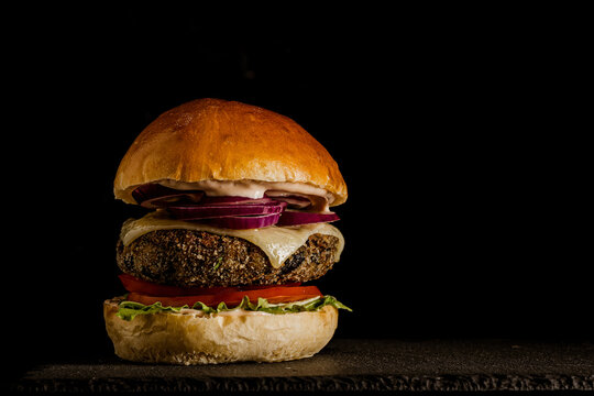 Burger z czarnej fasoli na czarnym tle 