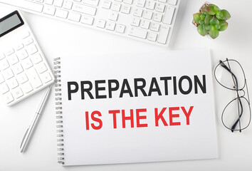 Office desk table with keyboard, notepad and calculator. Top view with text PREPARATION IS THE KEY