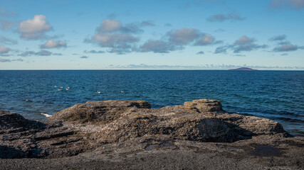 Fototapeta na wymiar Limestone cliffs at coast of the island Oland in Sweden with sun and blue sky.