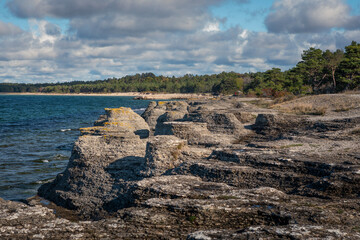 Fototapeta na wymiar Limestone cliffs at coast of the island Oland in Sweden with sun and blue sky.