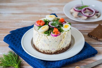 Snack, round Swedish salad cake with herring, potatoes, egg and sour cream mousse on black bread on...