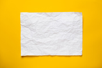 Frame from a crumpled, straightened sheet of white paper on a yellow background. Copy space. Top view. 