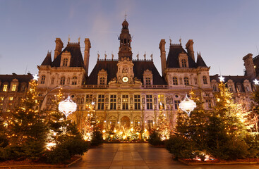 Parisian City Hall decorated with Christmas trees for winter holidays at night. Winter travel and...