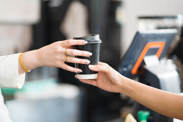 Caucasian waitress, a small company owner, a barista, and a bartender serving customer a coffee up at the bar counter in a cafe shop. Close Up hand holding a coffee cup