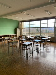 無人で机と椅子が並んだ寄木の床の日本の田舎の学校の教室の後方