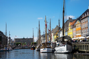 Nyhavn is a waterfront and canal in Copenhagen, Denmark. Colourful facades of houses and old ships along the canal. Wooden ships moored in the canal