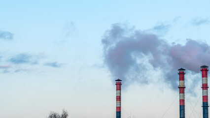 Smoking pipes from factories against a sunset sky. Close-up view of smoking factory chimney. Ecological problem.