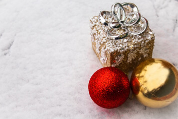Christmas balls red shiny and gold with a toy gift in the snow