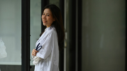 Photo of a young female doctor standing with arms crossed and holding a stethoscope in hand in the modern hospital.