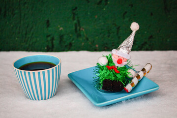 Christmas grandpa's toy on a blue saucer next to a cup of black coffee in the snow