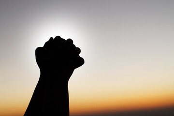 Praying hands with faith in religion and belief in God on sunset background. Power of hope or love and devotion.