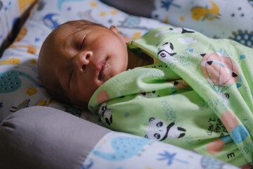 A newborn baby is sleeping comfortably with an adorable expression. Asian child two days old. 