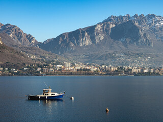Fototapeta na wymiar Small fishing boat moored in front of the city of Lecco, on Lake Como (Italy)