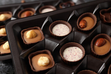 Chocolate candies in box all over background, close up