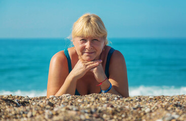 An elderly woman is resting on the beach. Selective focus.