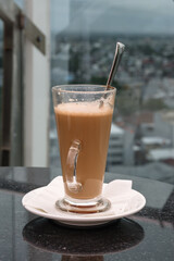 A glass of coffee latte on a table against a blurred background.